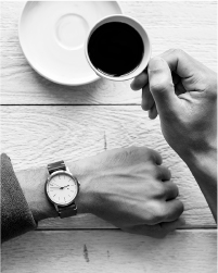 画像：男性が右手にコーヒーカップ、左手に腕時計。休憩をしている様子。